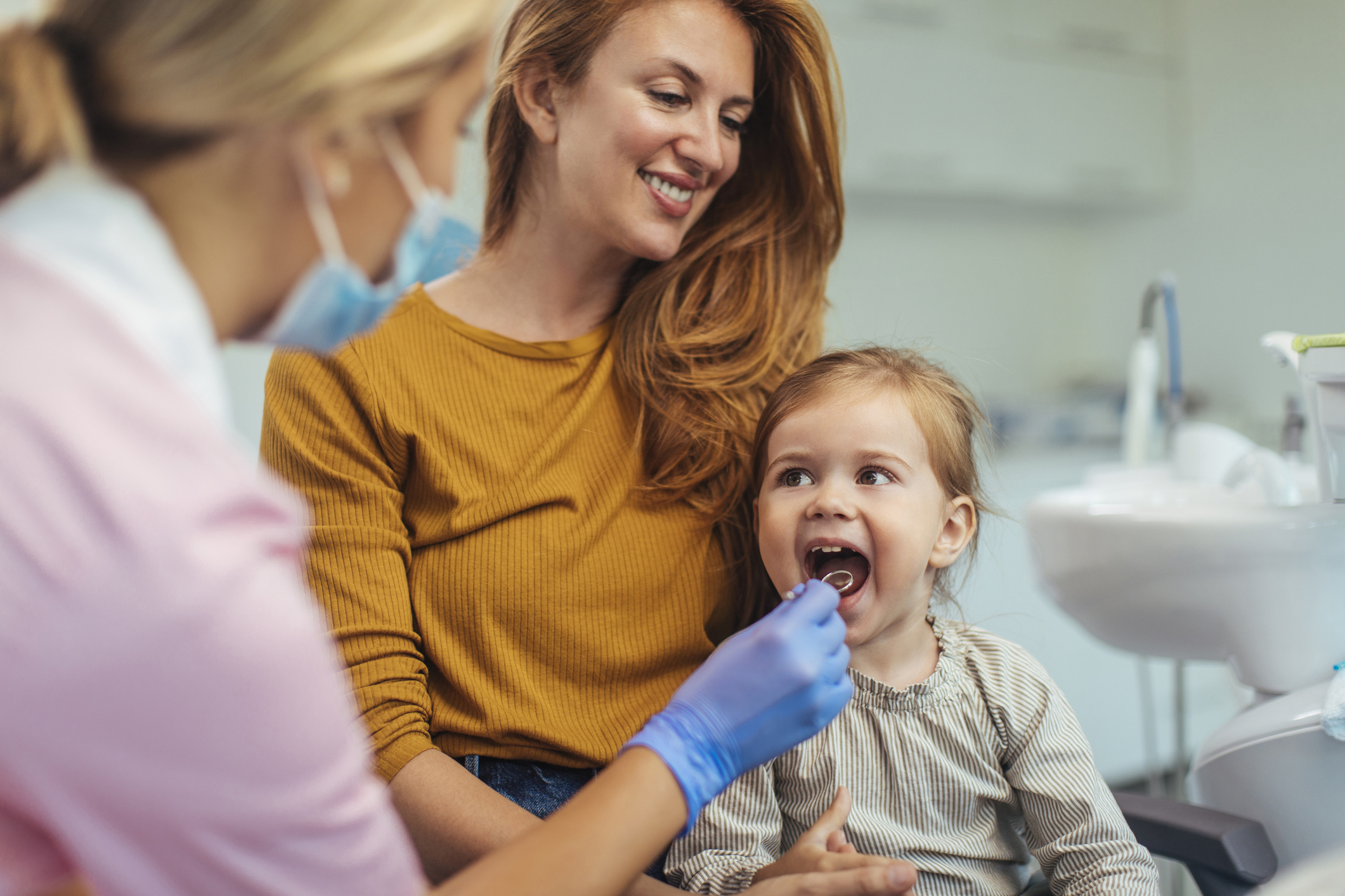 Young smiling Medicaid patient and caregiver with dentist